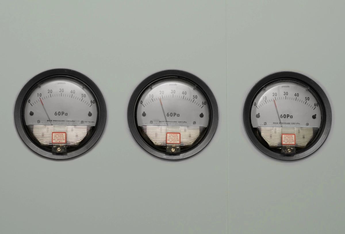 Three analog differential pressure gauges mounted on a cleanroom wall, each displaying readings in pascals.